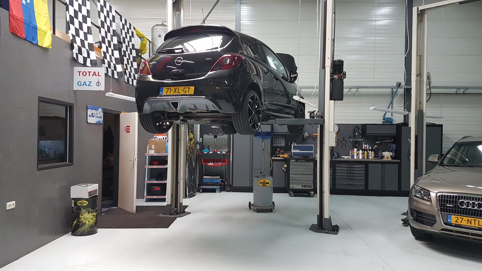 Werkplaats met een Opel Corsa op de brug en een Audi Q5 ernaast