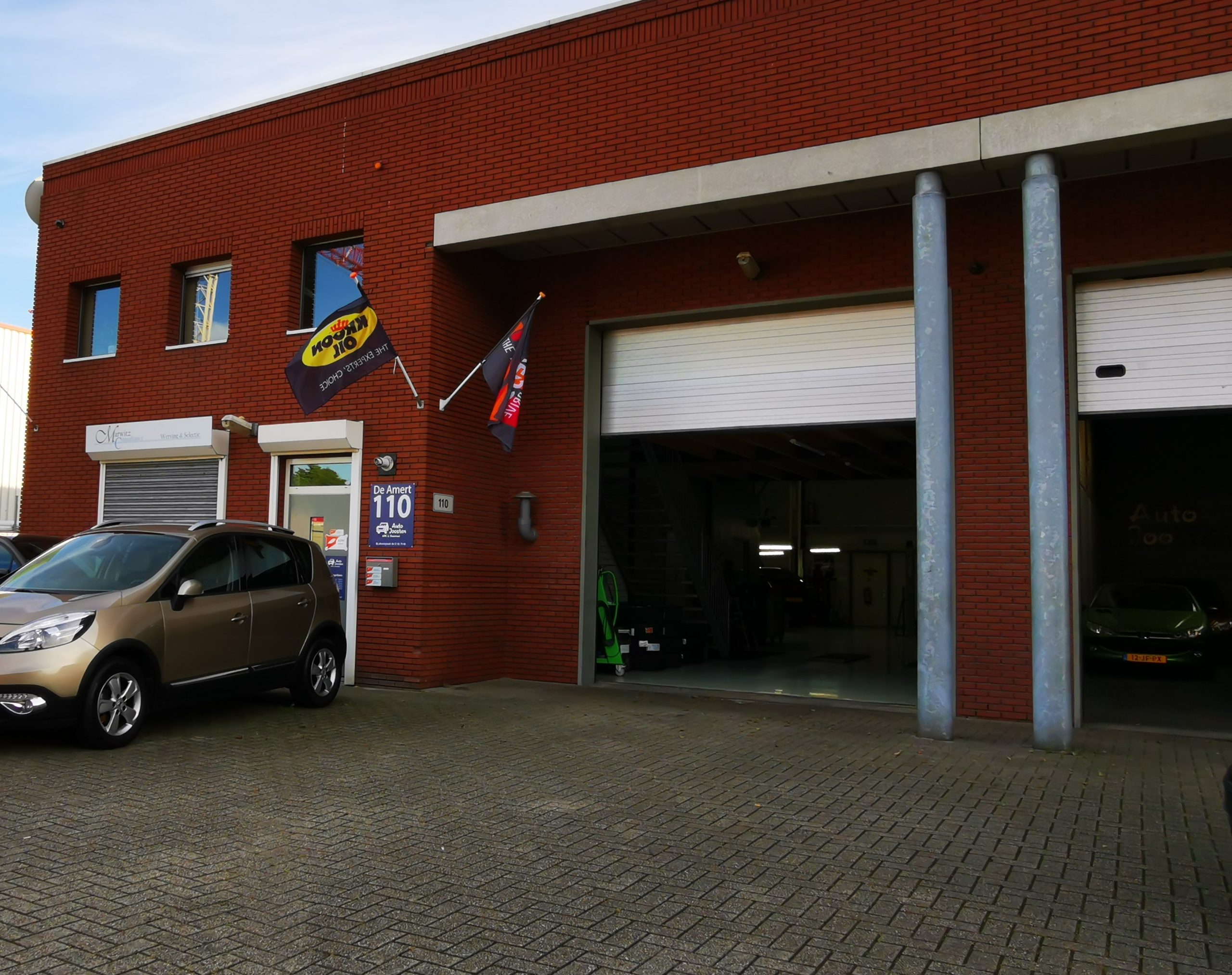 De gevel van Auto Joosten aan De Amert 110 in Veghel, rode baksteen met het huisnummer en het logo